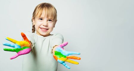 Happy girl showing her colorful painted hands. Child art school student smiling on white backgroundの写真素材