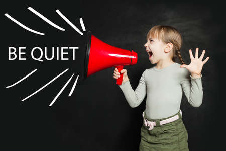 Be quiet concept. Funny little girl screaming loudly through a megaphone Be quiet!