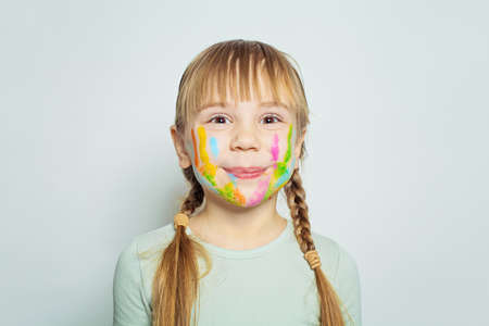 Adorable child little girl with colorful painted face on white backgroundの写真素材