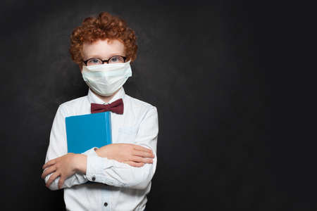 Smart child in medical protective face mask on blackboard backgroundの写真素材