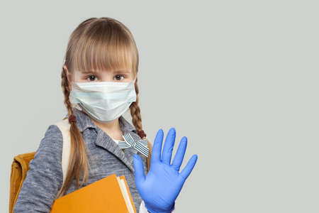 Little child girl in medical protective face mask showing stop gesture on white backgroundの写真素材