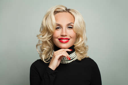 Perfect woman in pearls necklace holding her hand with manicured nails near face