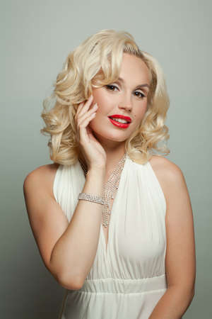 Fashion portrait of attractive model woman with blonde curly hairstyle on white background