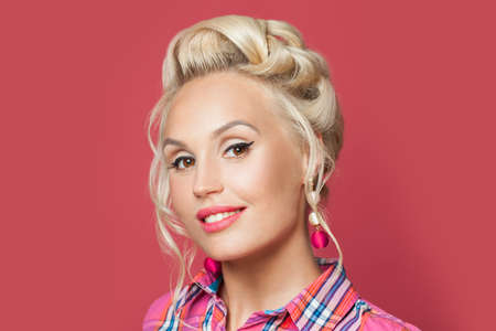 Pretty retro woman with red lips makeup and old-fashioned hairdo smiling. Pin up girl face closeup...