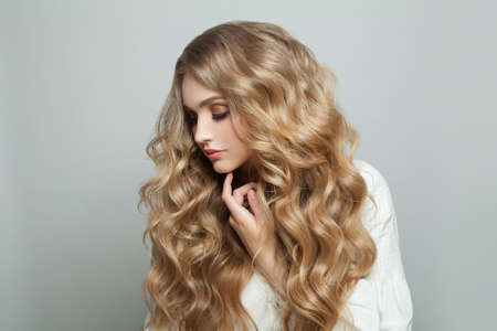 Young pretty woman with healthy curly blonde hair, beauty fashion portraitの写真素材