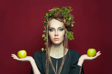 Halloween character woman with creative makeup and apples on red