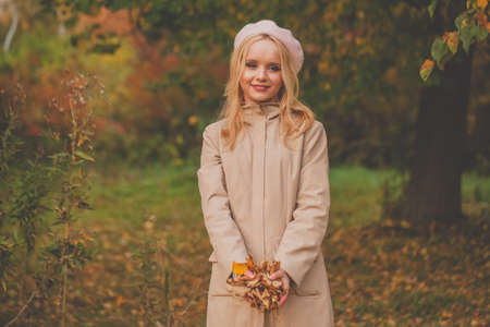Beautiful happy woman with autumn leaves in her hands on fall nature backgroundの写真素材