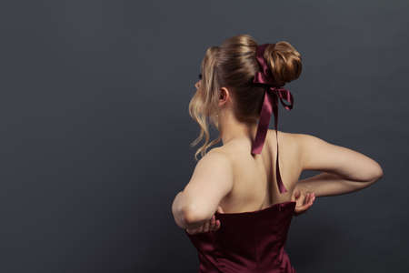 Beautiful woman putting on silky evening gown on black backgroundの写真素材