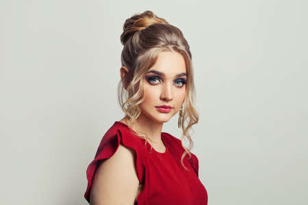 Pretty model woman with trendy fashionable makeup wearing red dress on white background
