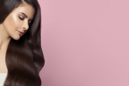 Perfect young woman with long healthy hairstyle on pink background, beautiful female faceの写真素材