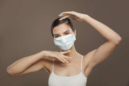 Healthy model woman in protective mask on brown backgroundの写真素材