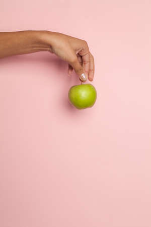 Apple in woman hand on pink, minimal background. Diet concept.の写真素材