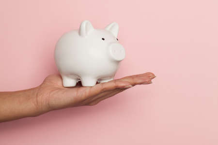 Money bank in female hand on pink backgroundの写真素材