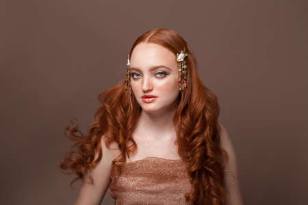 Portrait of young redhead woman with long hair on brown background. Perfect female model with blue eyes, nice clean skin, beautiful natural makeup, red hairの写真素材