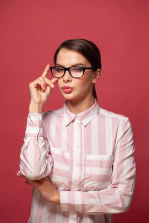 Clever successful young woman wearing glasses on red backgroundの写真素材