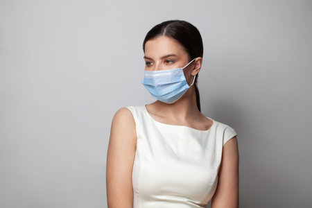 Young woman wearing medical face mask, studio portraitの写真素材