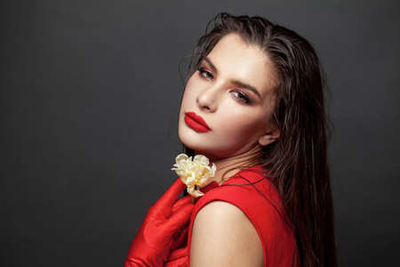 Portrait of young brunette woman in red classy fashion outfit on pink backgroundの写真素材