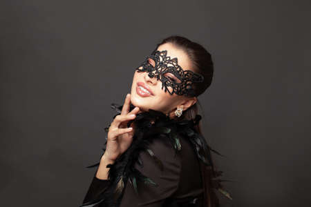 Laughing woman in black carnival mask. Glamorous beauty fashion model on black backgroundの写真素材