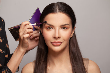 Professional makeup artist applying makeup on beautiful woman face close upの写真素材