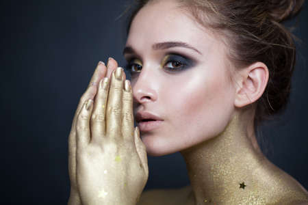 Beautiful glamorous woman with makeup and hands near face on dark backgroundの写真素材