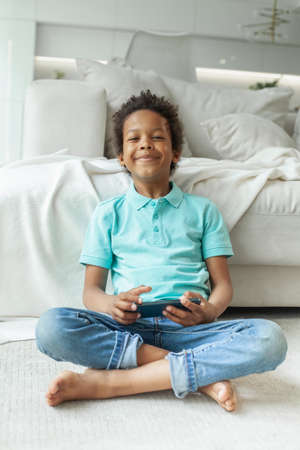 Happy kid boy using phone at homeの写真素材