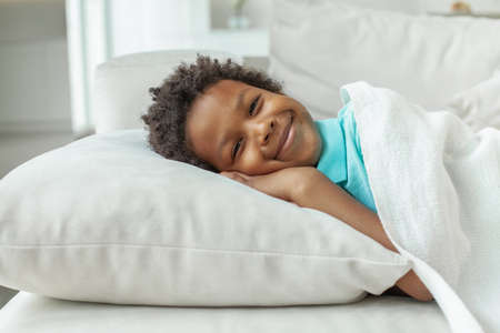 Little kid boy lying in his bed and smiling. Bedtimeの写真素材