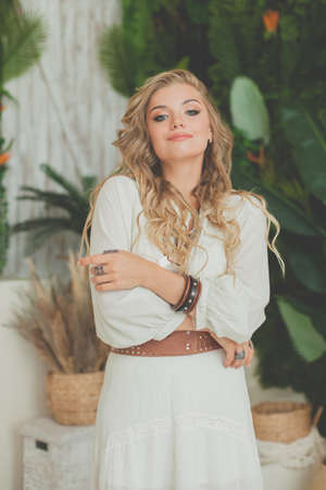 Glamorous woman with blonde curly hair smiling and resting in tropical resort