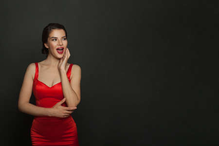 Happy surprised woman in red dress on black banner backgroundの写真素材