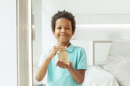 Cute child boy showing wooden house toy at homeの写真素材