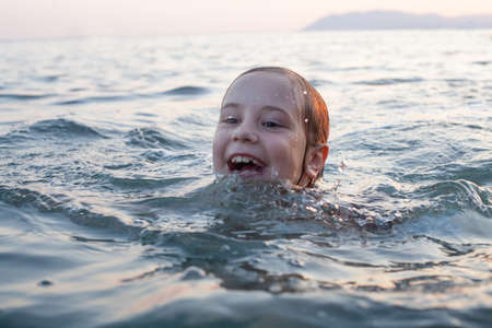 Cute child girl swimming on in the sea and having funの写真素材