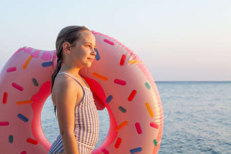 Happy little girl with colorful pink inflatable ring on a summer day during the holidaysの写真素材