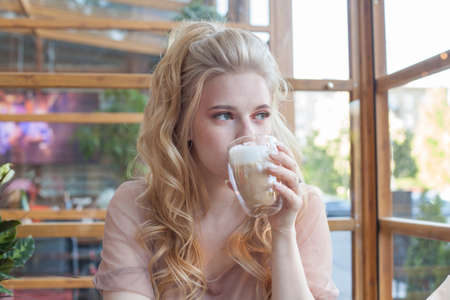 Young attractive model woman with cup of coffee sitting in cafeの写真素材