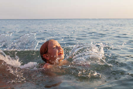 Adorable girl splashing in a sea on a sunny summer dayの写真素材