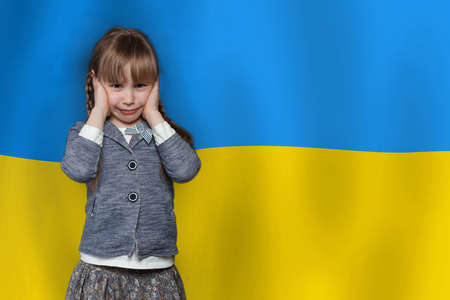 No war in Ukraine concept. Little child girl crying on Ukrainian flag backgroundの写真素材