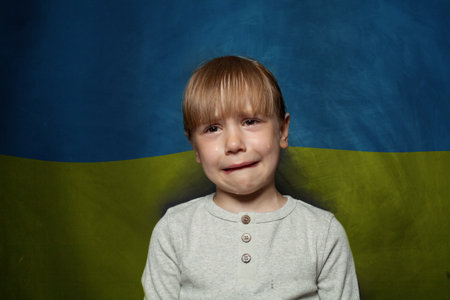 Afraid child girl crying on Ukrainian flag background. Stop war in Ukraine conceptの写真素材