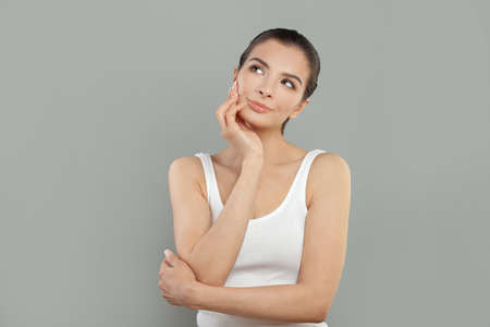 Young beautiful woman with hand on chin thinking about question, pensive expression. Smiling with thoughtful face. Doubt concept.の写真素材