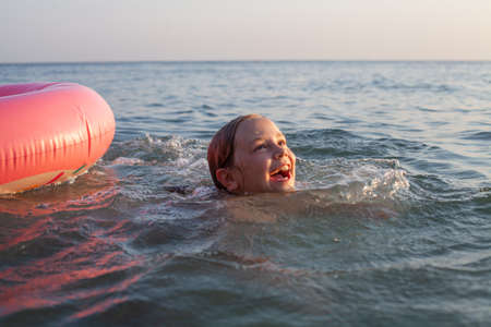 Happy laughing child learns swimming on the seaの写真素材