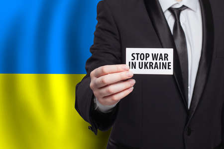 Stop war in Ukraine. Person holding banner on Ukrainian flag background