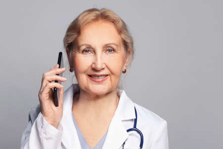 Happy female physician or surgeon gives prescription via mobile phone, closeup portraitの写真素材