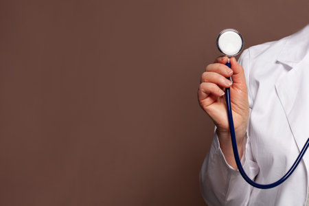Doctor hand holding stethoscope on brown backgroundの写真素材