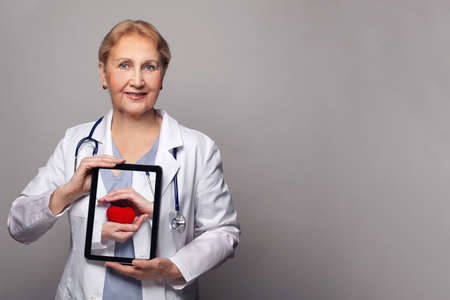 Doctor cardiologist holds digital tablet with heartの写真素材