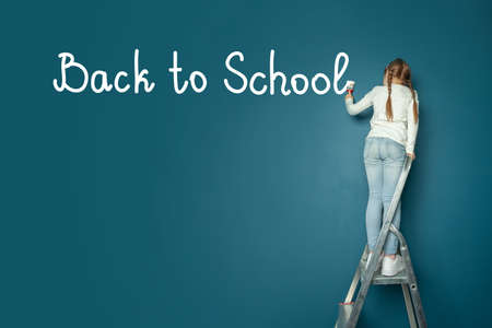 Schoolgirl writing inscription Back to school on blue banner background with copy spaceの写真素材
