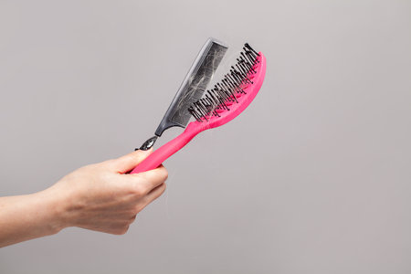 Hand with hair comb and hair brush, hair loss concept