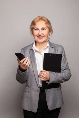 Happy senior business woman with smartphone portraitの写真素材