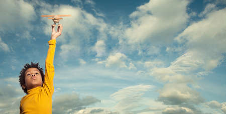 Little African American child playing airplane, outdoor portraitの写真素材