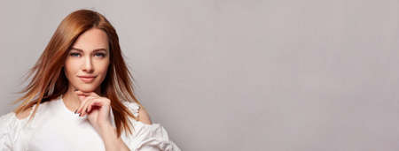 Beautiful young redhead woman with blonde hair against grey studio wall backgroundの写真素材