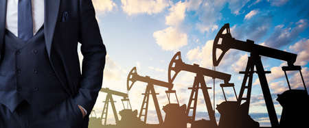Businessman against oil industry equipment silhouette with blue sky clouds background