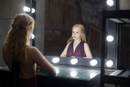 Back view of beautiful singer in standing in front of mirrorの写真素材