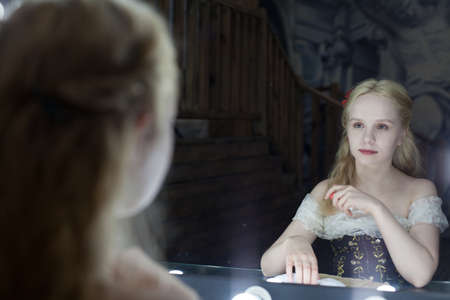 Young actress woman sits on a chair in front of a mirror in the dressing room