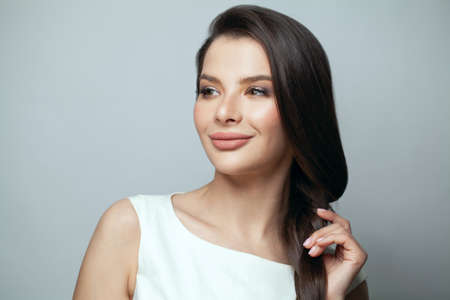 Fashion beauty portrait of positive model woman with smooth straight hair and makeup on gray background portraitの写真素材